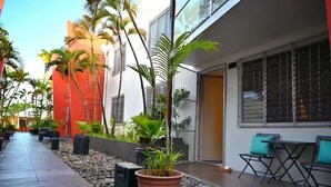A pathway lined with potted plants and a seating area with chairs and a table. - Lavish Lodge (Suva)