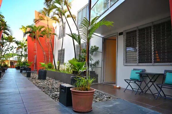 A pathway lined with potted plants and a seating area with chairs and a table.