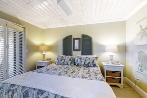 A bedroom with a bed, two nightstands, a ceiling fan, and a wall with a starfish decoration. - Beachfront Condo With Outdoor Pool, Patio & Washer/dryer - Dog-friendly (Fernandina Beach)
