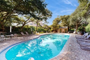 A swimming pool with lounge chairs and a small building in the background. - Beachfront Condo With Outdoor Pool, Patio & Washer/dryer - Dog-friendly (Fernandina Beach)