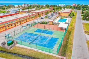 A multi-story hotel with a tennis court, parking area, and a view of the ocean. - Condo Across the Street From the Beach With Pool, Tennis, &. Washer/dryer (St. Augustine)