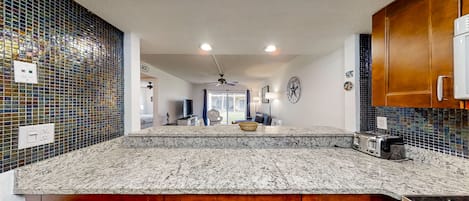 Una cocina moderna con encimera de granito, armarios de madera y salpicadero con mosaicos azules.