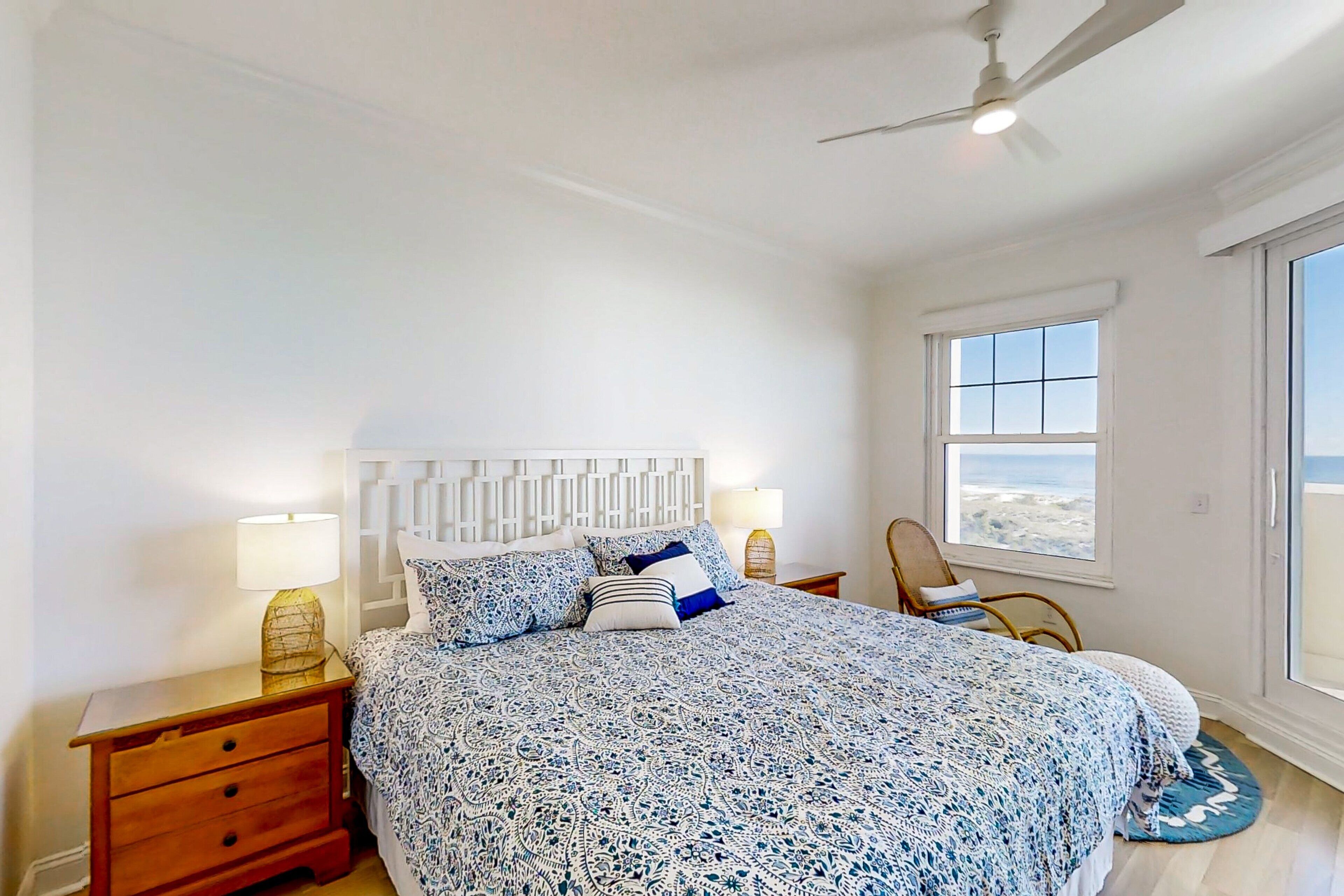A bedroom with a bed, nightstands, a chair, and a window with a view.