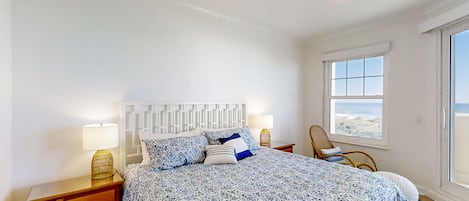 A bedroom with a bed, nightstands, a chair, and a window with a view.