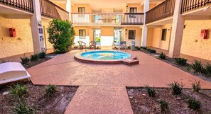 A courtyard with a swimming pool, outdoor seating, and a two-story building with balconies. - Cool Waves Oceanfront Retreat - St Augustine Beach 2 Pools 5 Hot Tubs! On the Beach (St. Augustine)