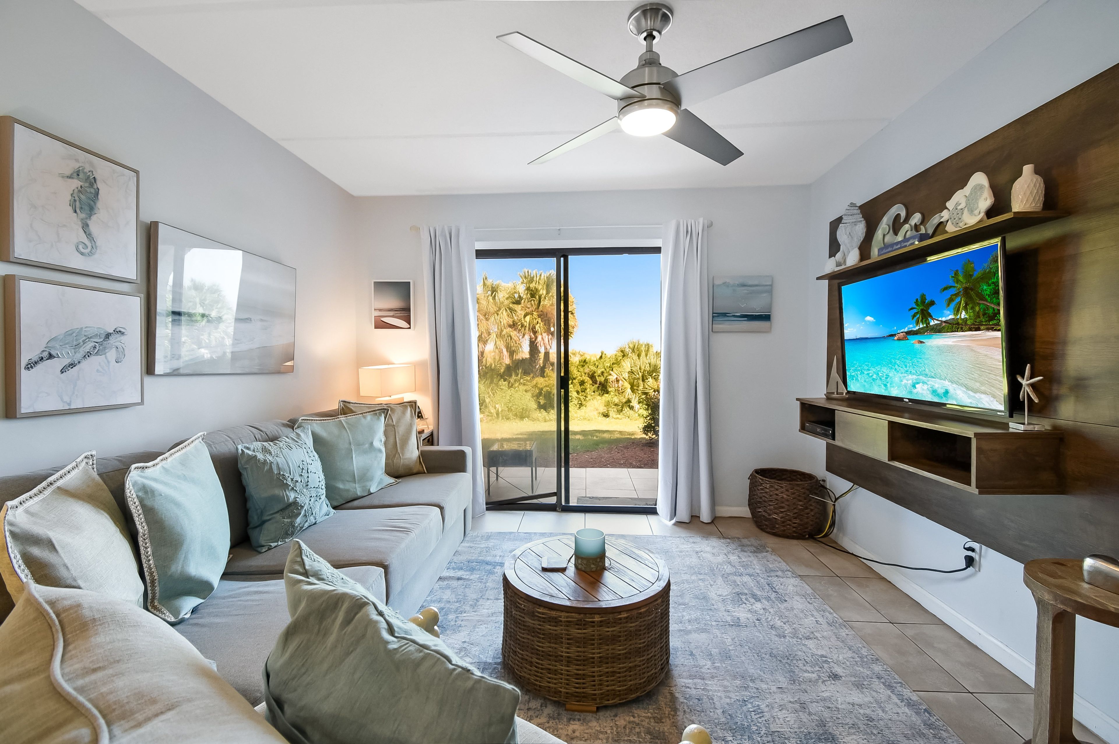 A living room with a sofa, a television, and a ceiling fan.