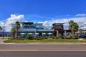 A modern building with outdoor seating and palm trees. - Cool Waves Oceanfront Retreat - St Augustine Beach 2 Pools 5 Hot Tubs! On the Beach (St. Augustine)