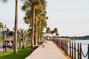 A waterfront promenade with palm trees, a paved walkway, and a chain barrier along the water's edge. - Cool Waves Oceanfront Retreat - St Augustine Beach 2 Pools 5 Hot Tubs! On the Beach (St. Augustine)