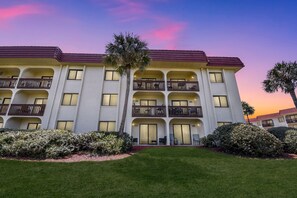 A multi-story hotel with a flat facade, balconies, and a well-maintained lawn. - Cool Waves Oceanfront Retreat - St Augustine Beach 2 Pools 5 Hot Tubs! On the Beach (St. Augustine)