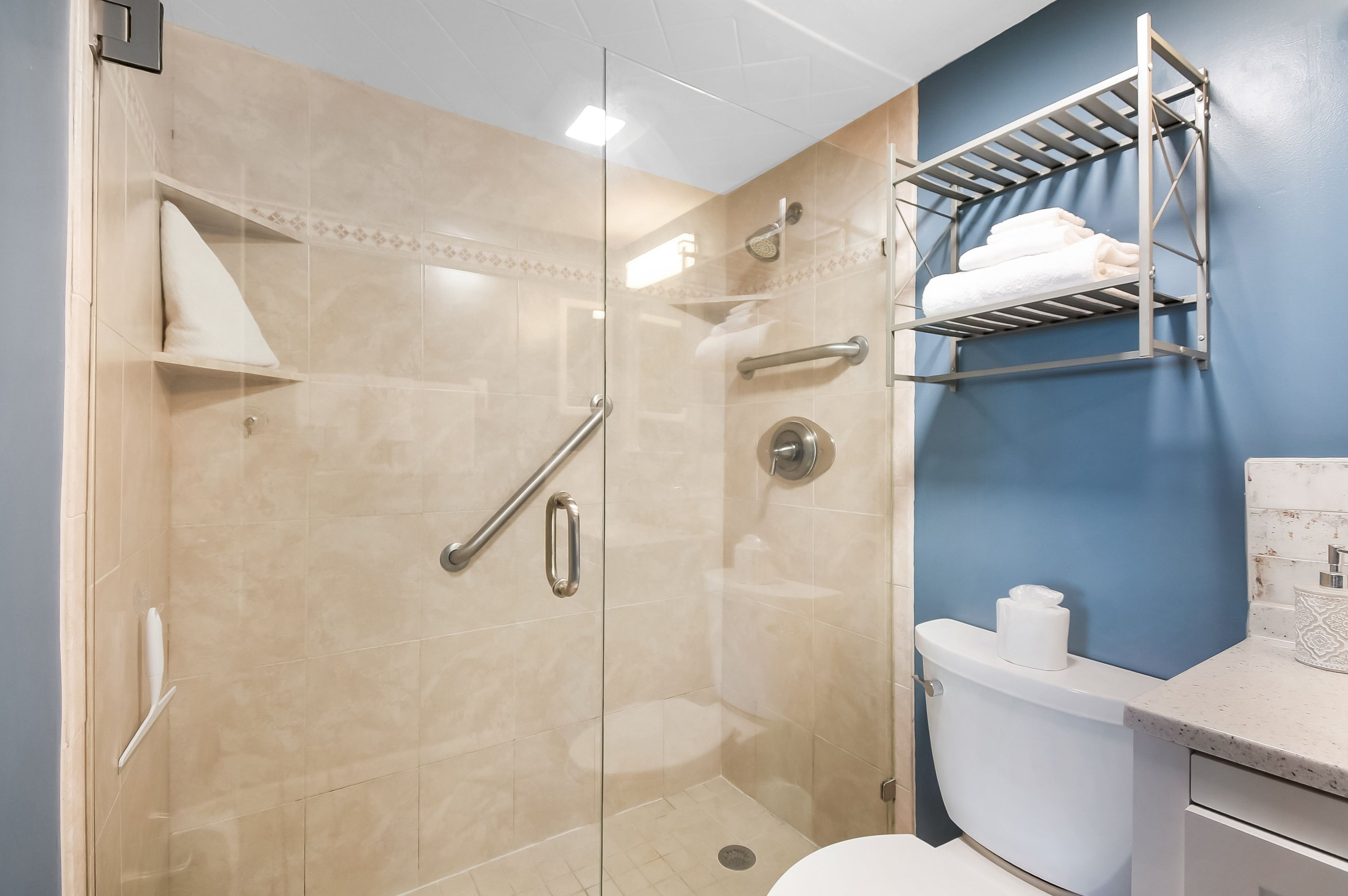 A modern bathroom with a glass-enclosed shower, a white toilet, and a towel rack on the wall.
