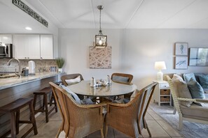A modern kitchen with white cabinets, a stainless steel microwave, and a hanging light fixture. - Cool Waves Oceanfront Retreat - St Augustine Beach 2 Pools 5 Hot Tubs! On the Beach (St. Augustine)