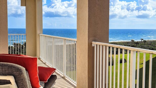 Ein Balkon mit Blick auf das Meer und eine Rasenfläche.