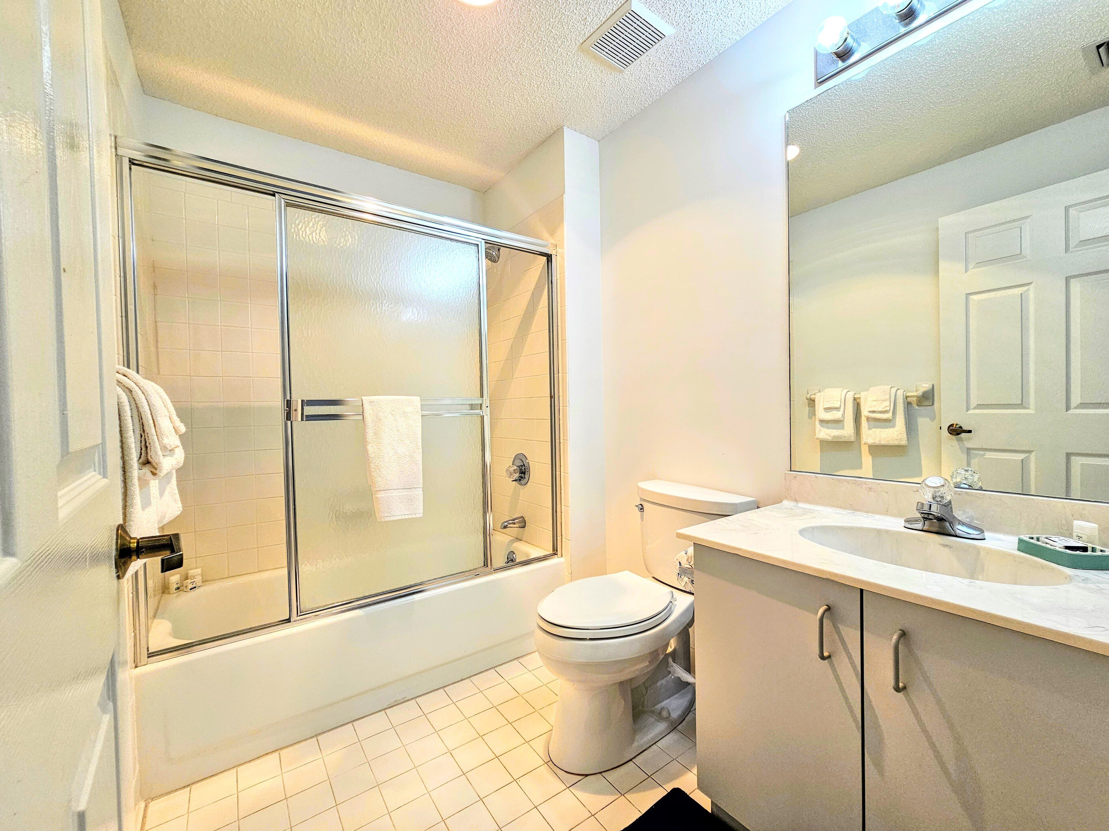 Une salle de bain avec une douche à parois de verre, des toilettes et un lavabo avec un miroir.