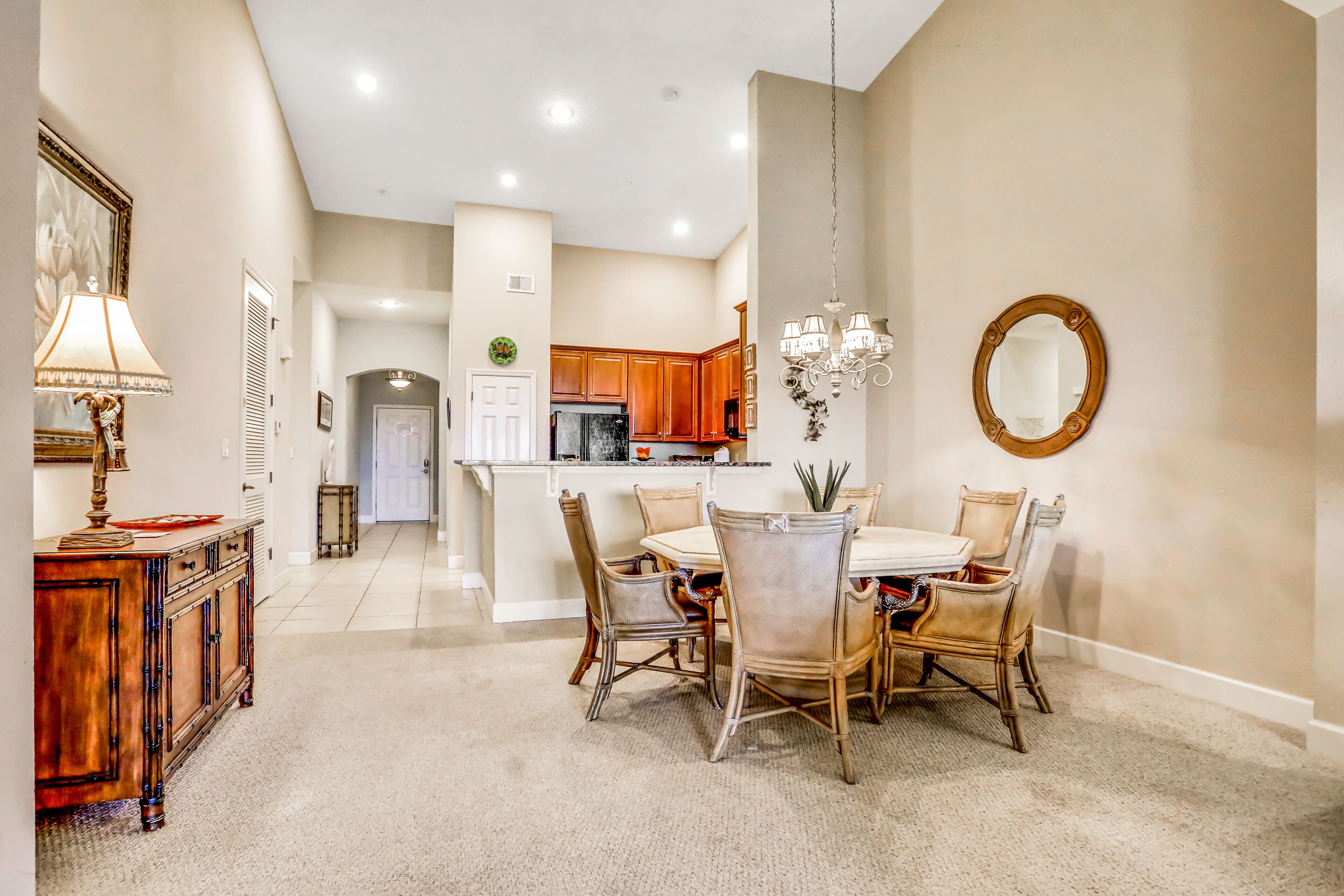 A dining area with a table and chairs, a chandelier, and a mirror on the wall.