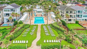 A resort with a central swimming pool, multiple guest rooms, and a well-maintained lawn with lounge chairs. - Dog-friendly Condo on the Golf Course With Ocean View, Pools, gym & Beach Access (Palm Coast)