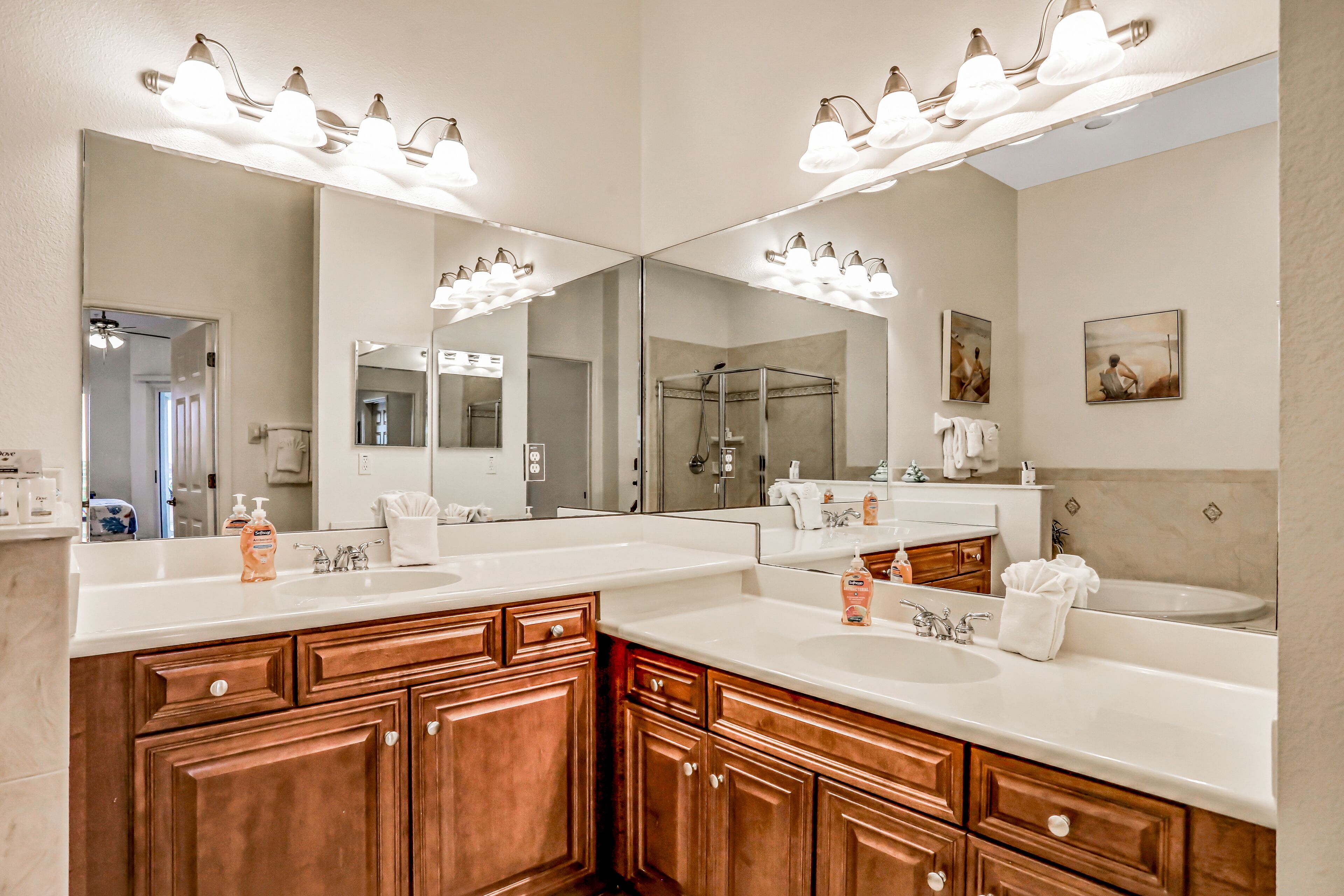 A bathroom with a double vanity, a shower, and a large mirror.