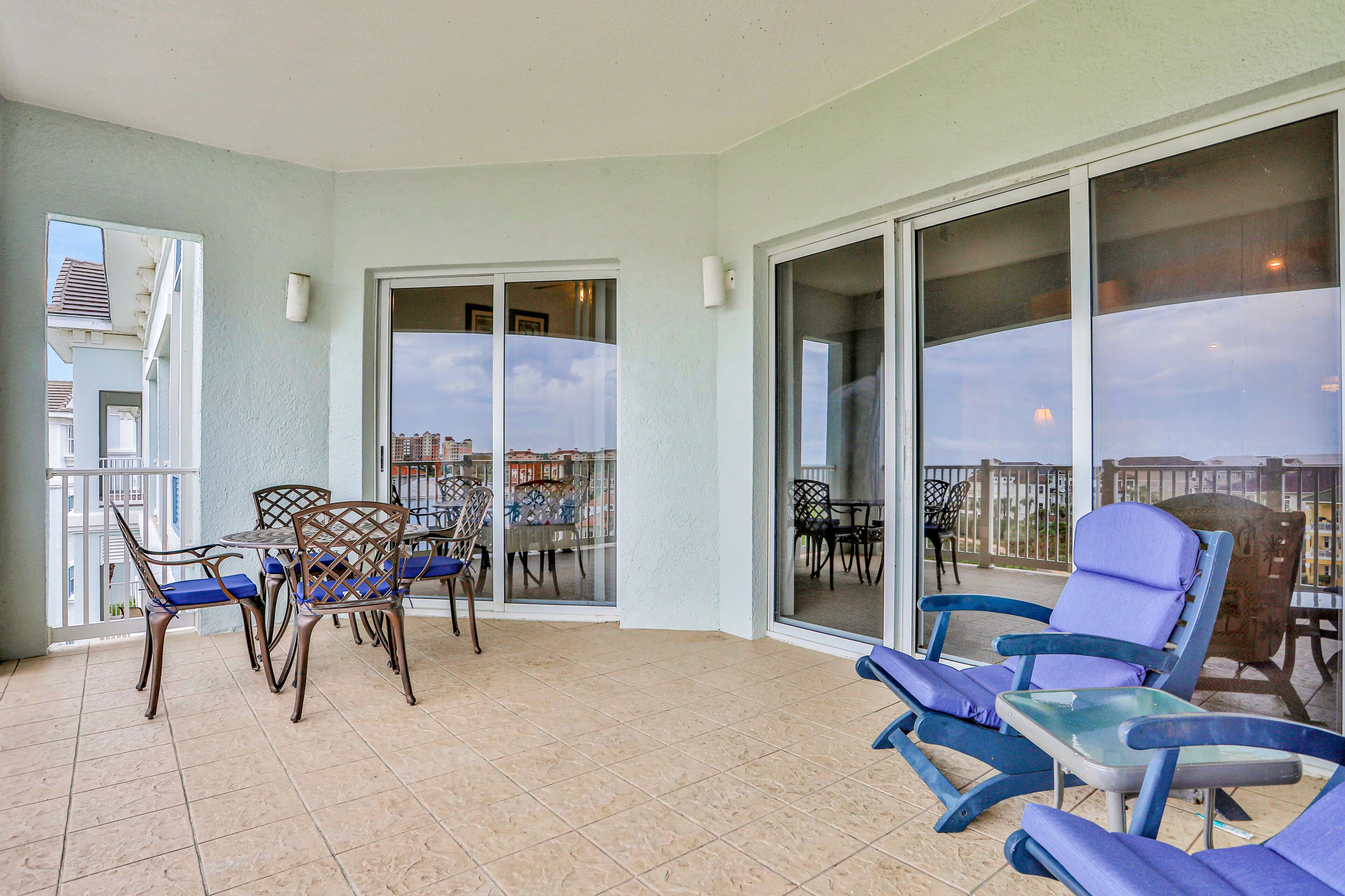 A balcony with a table and chairs, a view of the city, and a door leading to another room.