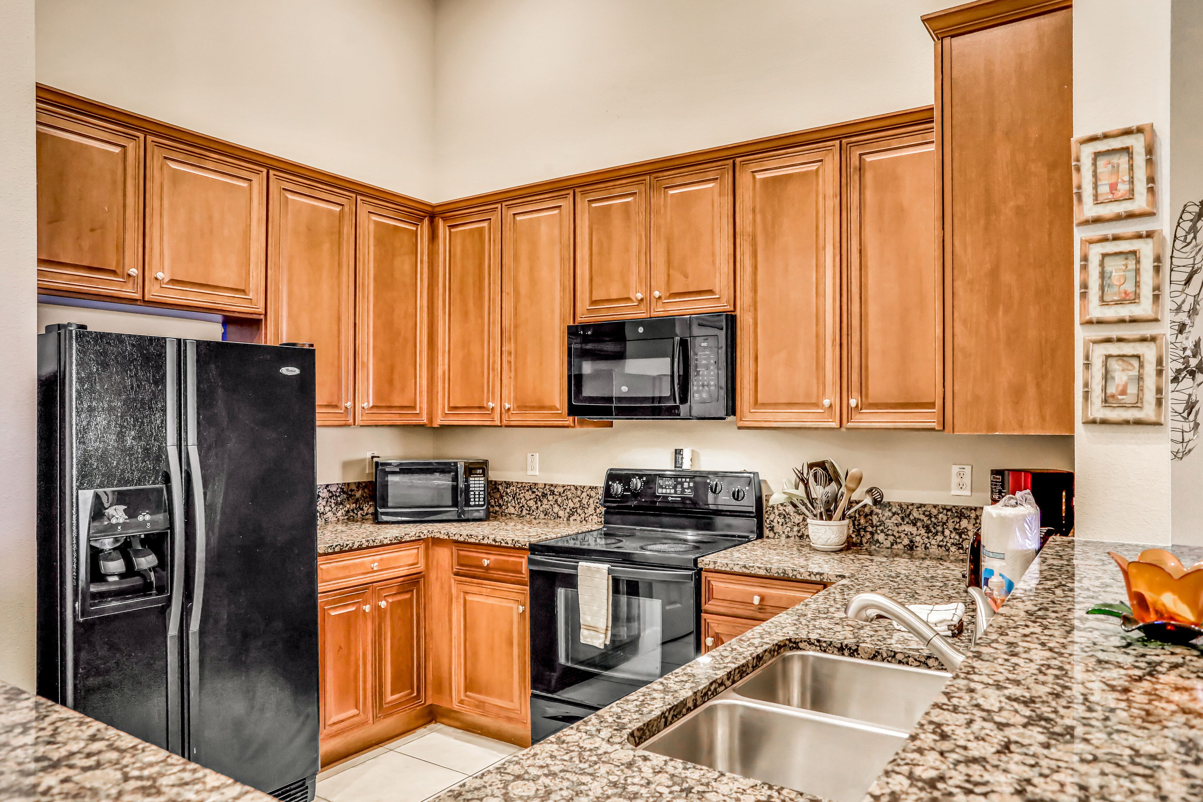 A kitchen with wooden cabinets, a stainless steel refrigerator, a microwave, an oven, and granite countertops.