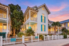 A row of white colonial-style buildings with balconies, a white picket fence, and a sign indicating rental availability. - Charleston-style Cottage w/ Lovely Decks, Steps to the Beach & Pools (St. Simons Island)
