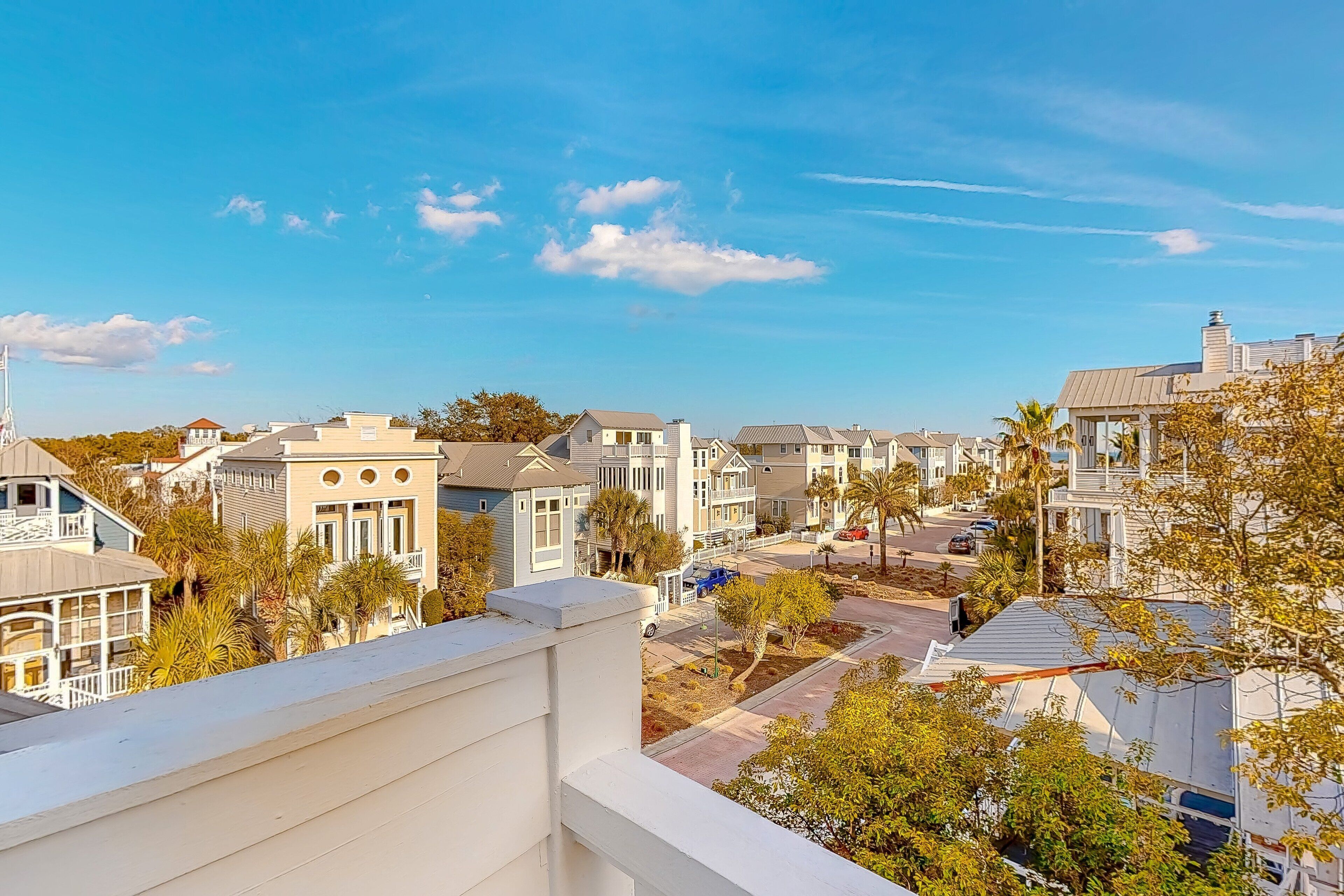 A residential area with multiple houses, a clear sky, and a few palm trees.
