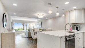 A modern kitchen with white cabinetry, a central island, and a dishwasher. - Completely Renovated Oceanfront Condo W/washer/dryer & Shared Pool/tennis (Fernandina Beach)