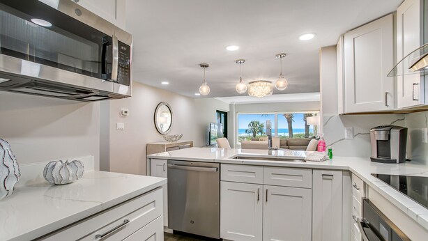 A modern kitchen with stainless steel appliances, white cabinetry, and a large island with a sink. - Completely Renovated Oceanfront Condo W/washer/dryer & Shared Pool/tennis (Fernandina Beach)