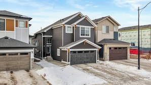 A residential area with houses, a garage, and a driveway. - 5BR Family Home w Kids Play Den (Calgary)
