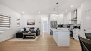 A modern kitchen with white cabinetry, stainless steel appliances, and a central island. - 5BR Family Home w Kids Play Den (Calgary)