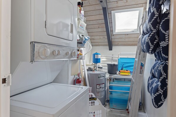 A compact kitchen with a built-in washer, a water heater, and storage cabinets. - A-frame Beach House Steps From the Ocean With Deck & Central AC (Ponte Vedra Beach)