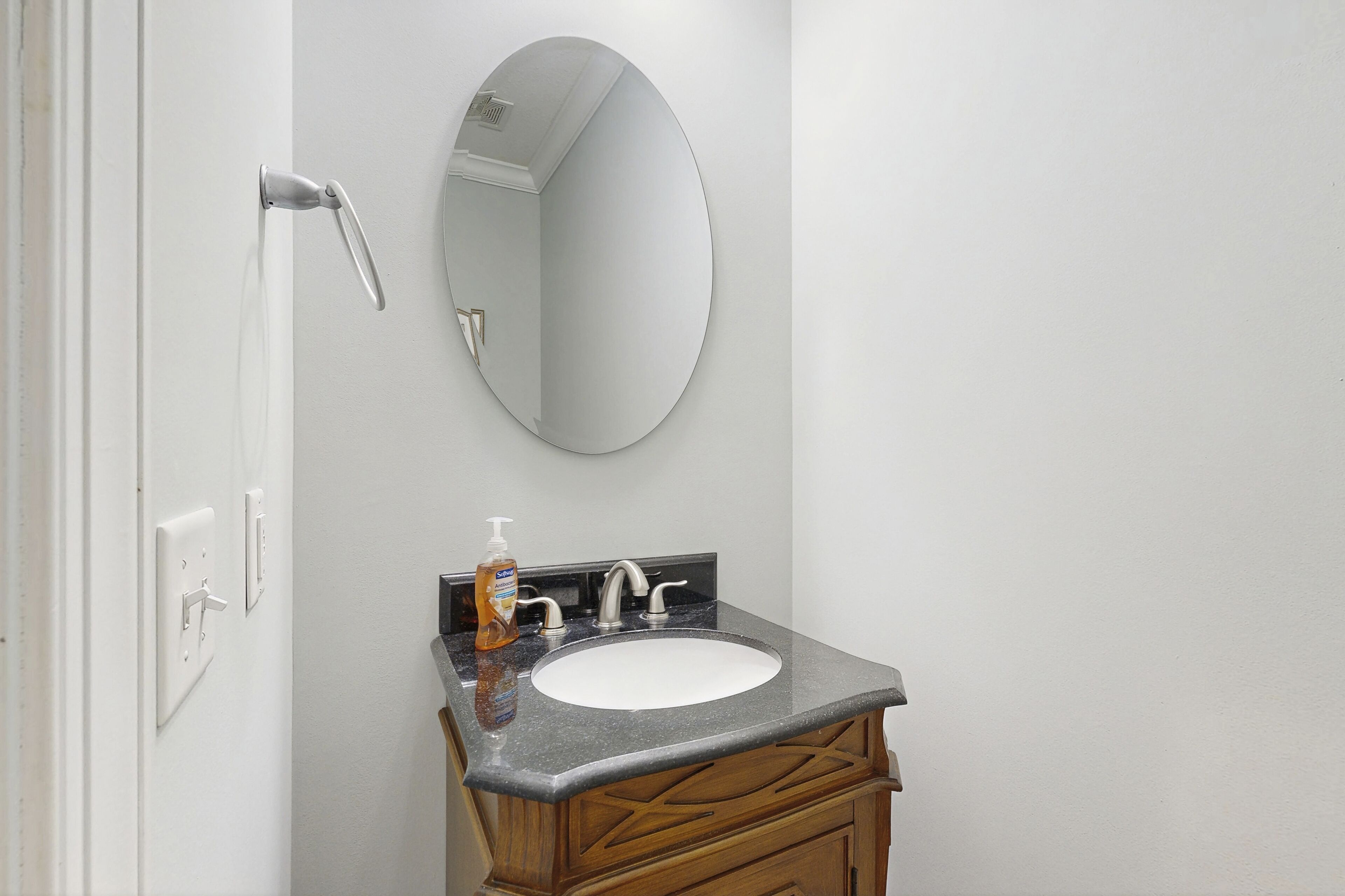 A bathroom with a white sink, a mirror, a faucet, and a soap dispenser.