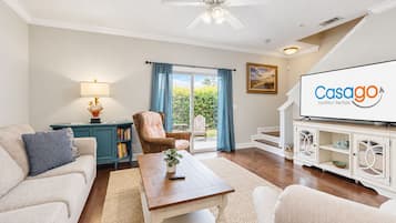 Sala de estar con sofá, sillón, mesa de centro y televisor mostrando 'Casago Vacation Rentals'.
