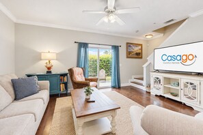Sala de estar con sofá, sillón, mesa de centro y televisor mostrando 'Casago Vacation Rentals'.