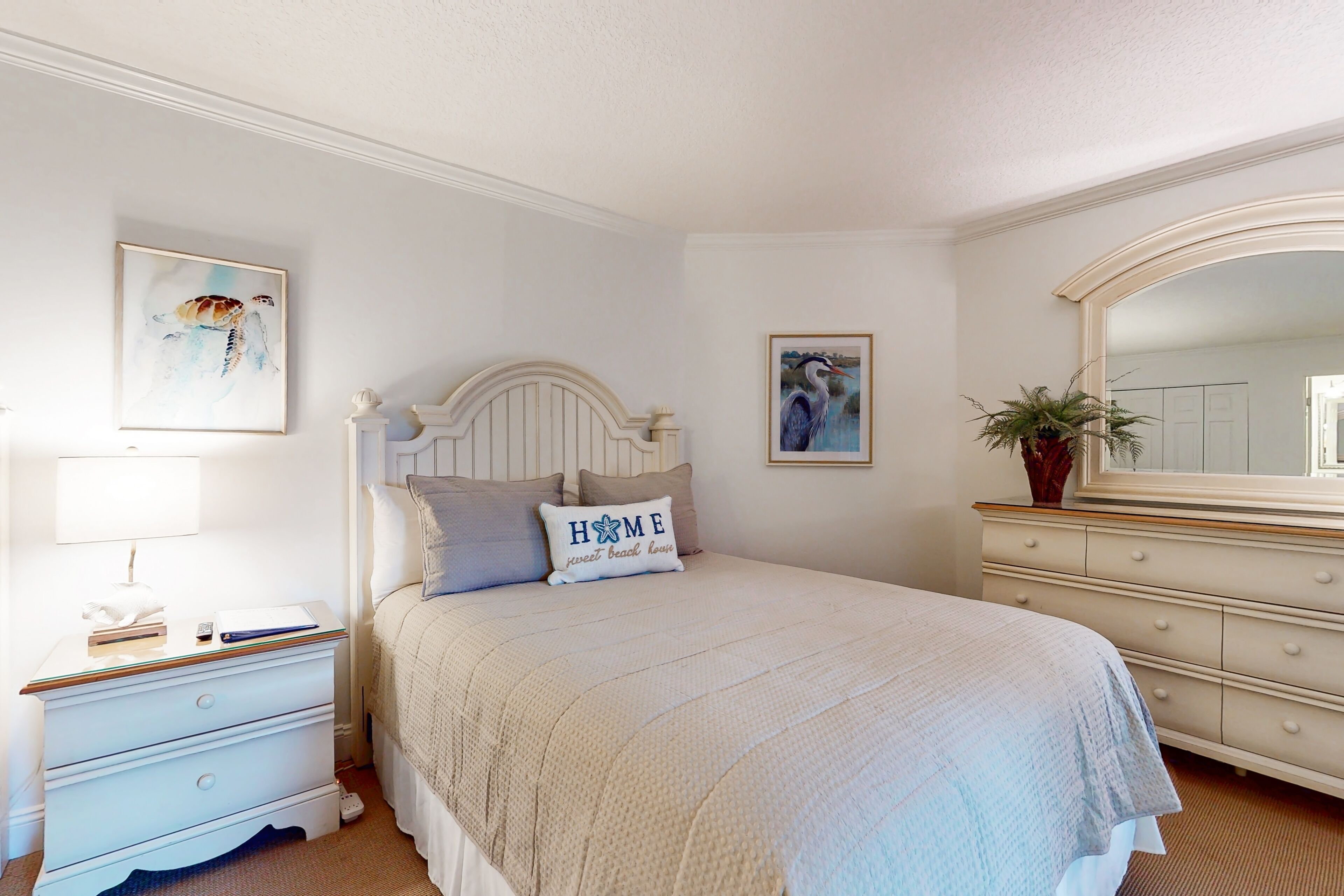 A bedroom with a bed, nightstand, dresser, and a mirror.