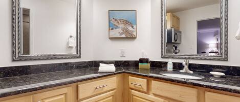 A bathroom with two large mirrors, a sink, and wooden cabinets.
