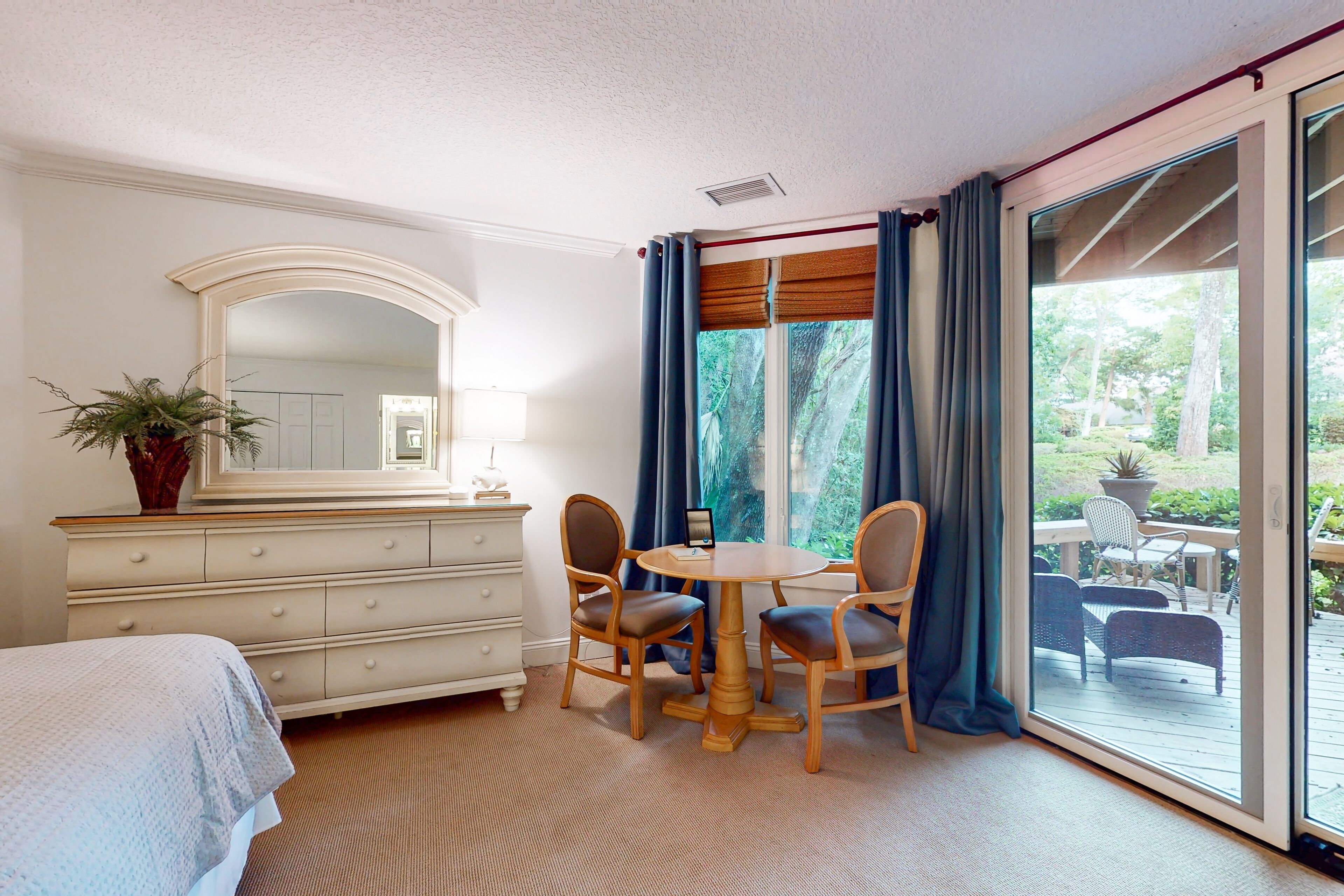 Ein Schlafzimmer mit Bett, Schminktisch, Spiegel und einem Esstisch mit Stühlen.