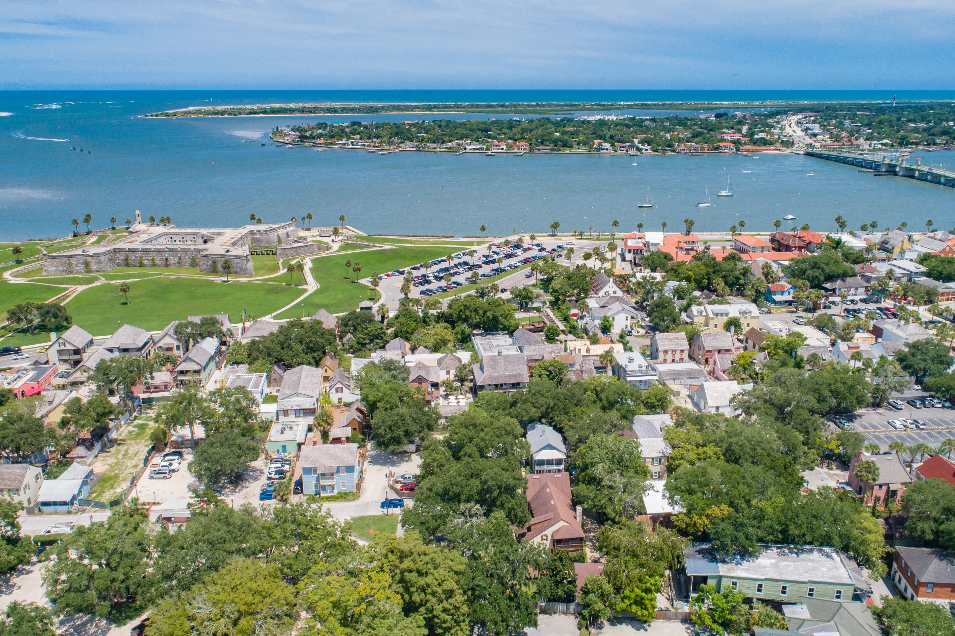 An aerial view of a coastal town with a historic fort, residential buildings, and a marina.