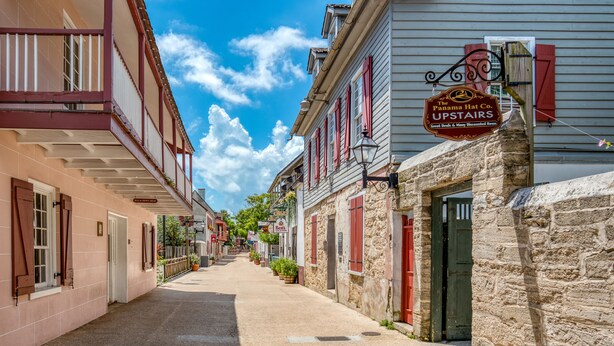 Eine enge Straße, gesäumt von historischen Gebäuden, darunter ein Schild mit der Aufschrift Panama Hat Co. im Obergeschoss.