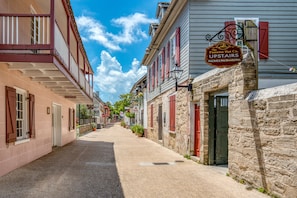 Una stretta via fiancheggiata da edifici storici, uno dei quali espone un cartello con la scritta 'The Panama Hat Co. Upstairs'.