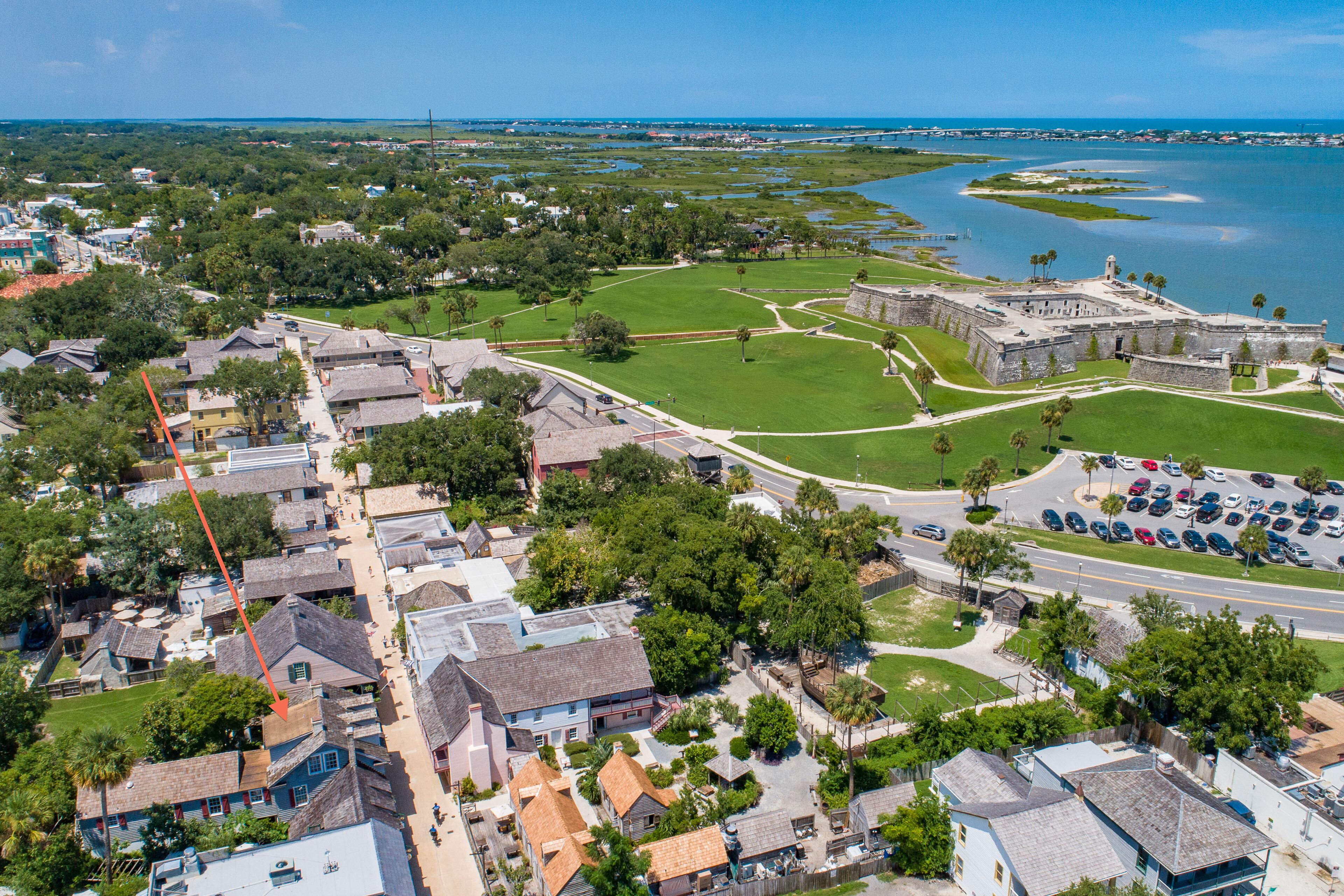 An aerial view of a historic town with a prominent fort, narrow streets, and a marina.
