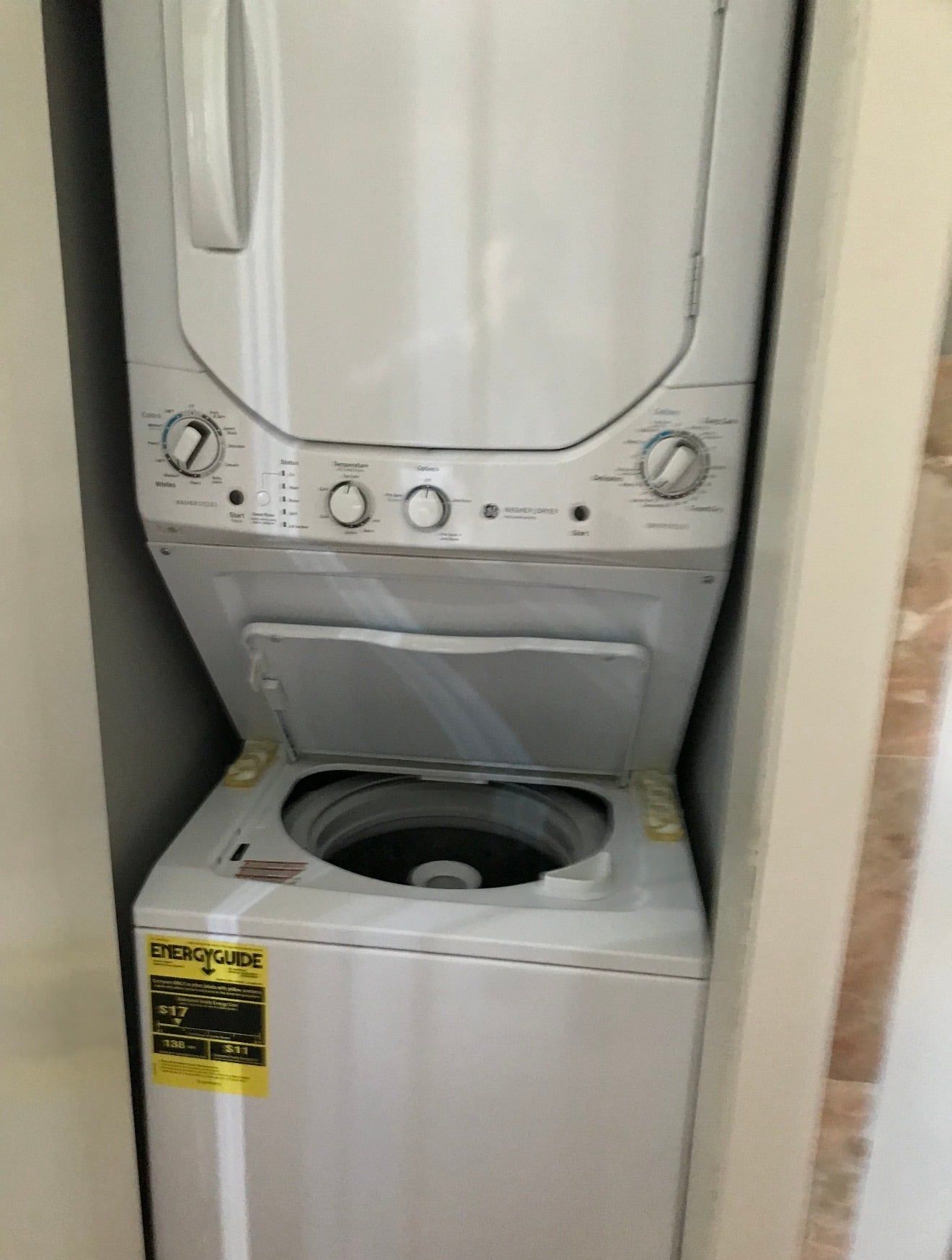 A front view of a compact, white, front-loading washing machine with a control panel featuring multiple dials and buttons.