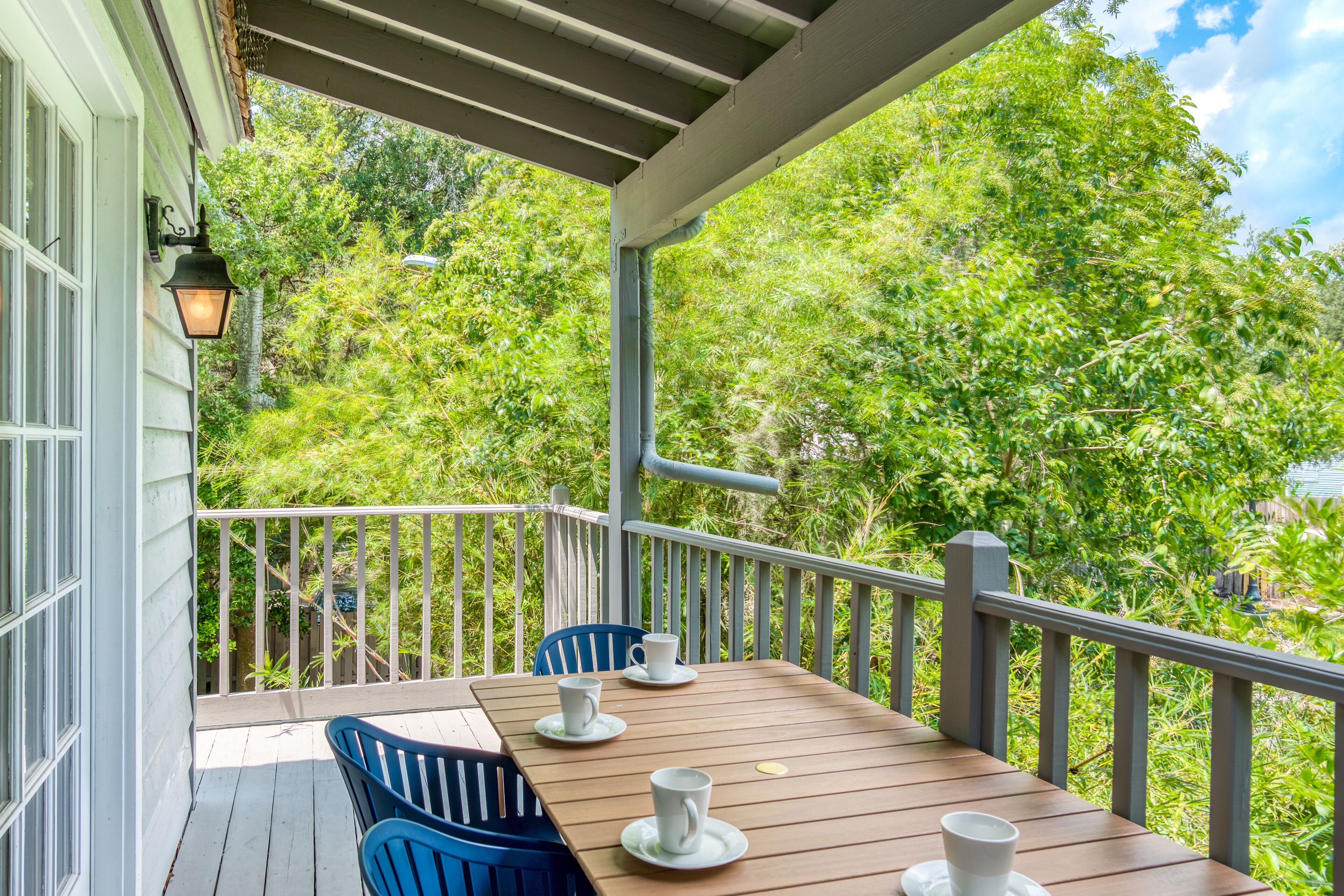 A wooden deck with a table and chairs, surrounded by lush greenery.