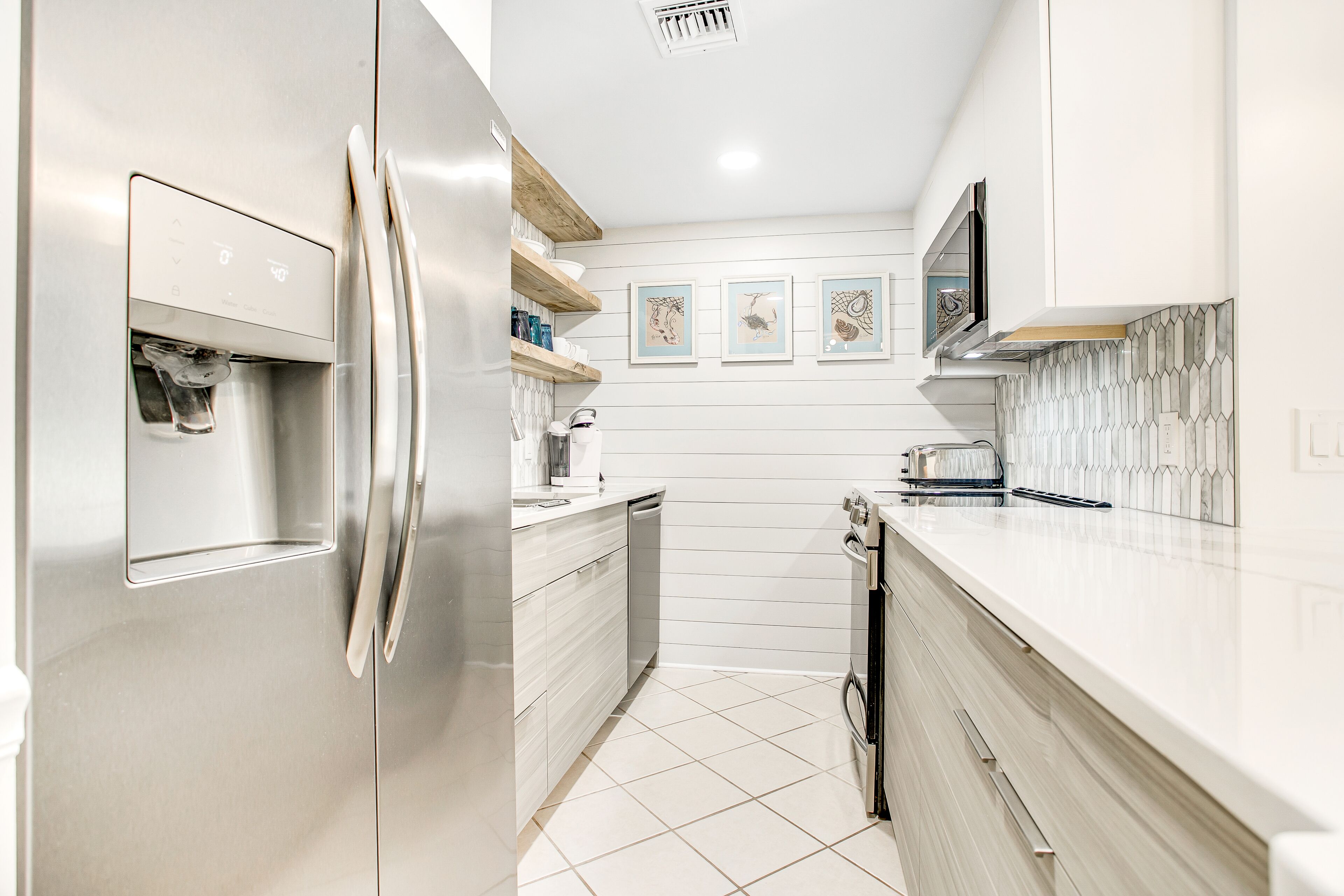 Una cocina moderna con electrodomésticos de acero inoxidable, armarios blancos y salpicadero de azulejos.