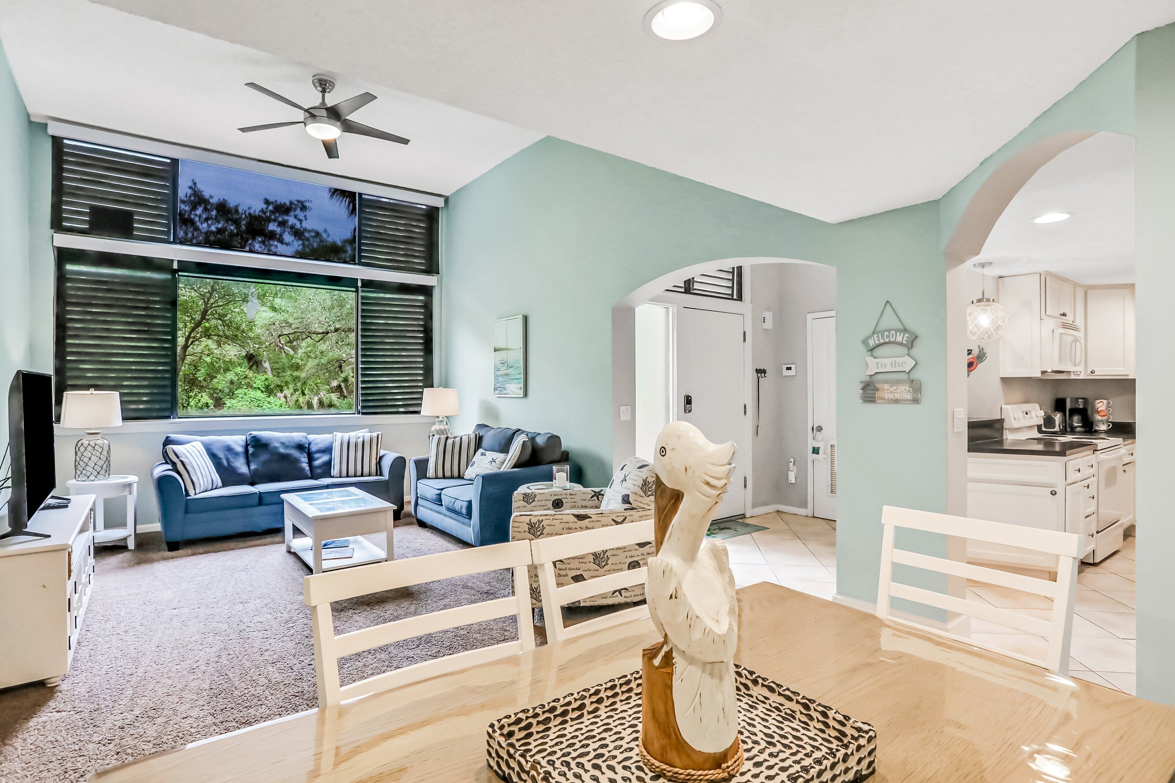 A modern living room with a blue sofa, white coffee table, and a decorative bird sculpture.