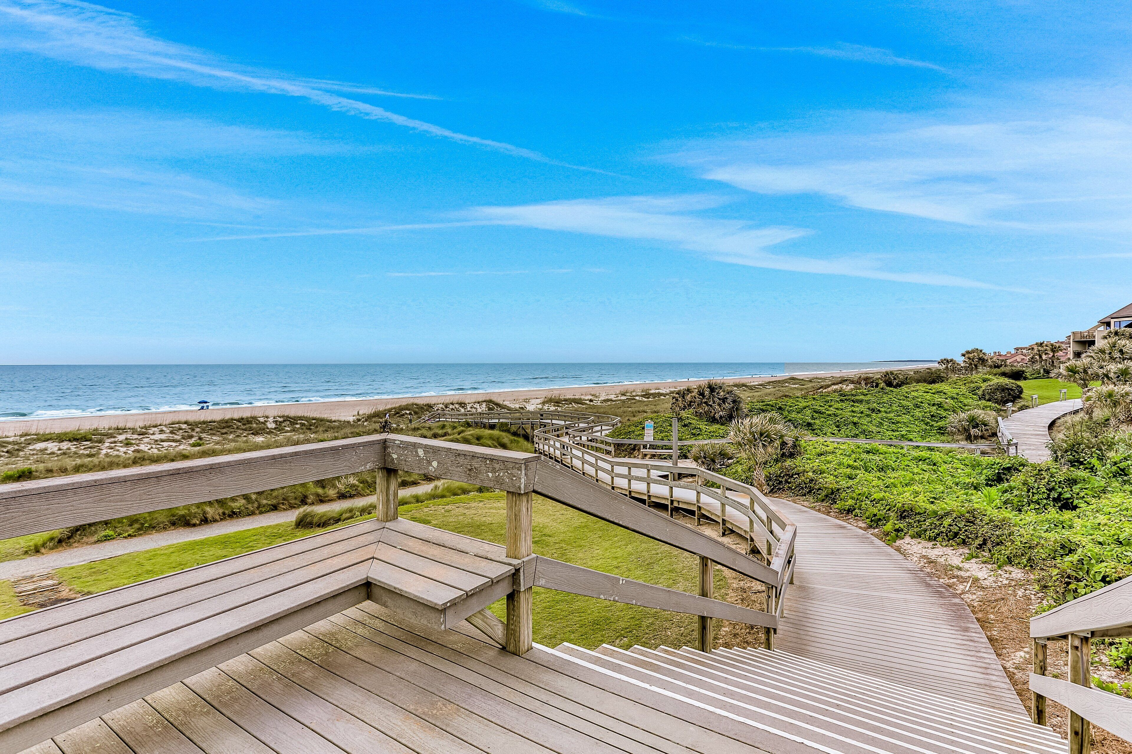 Una passerella in legno che conduce a una spiaggia, con vista chiara sull'oceano.