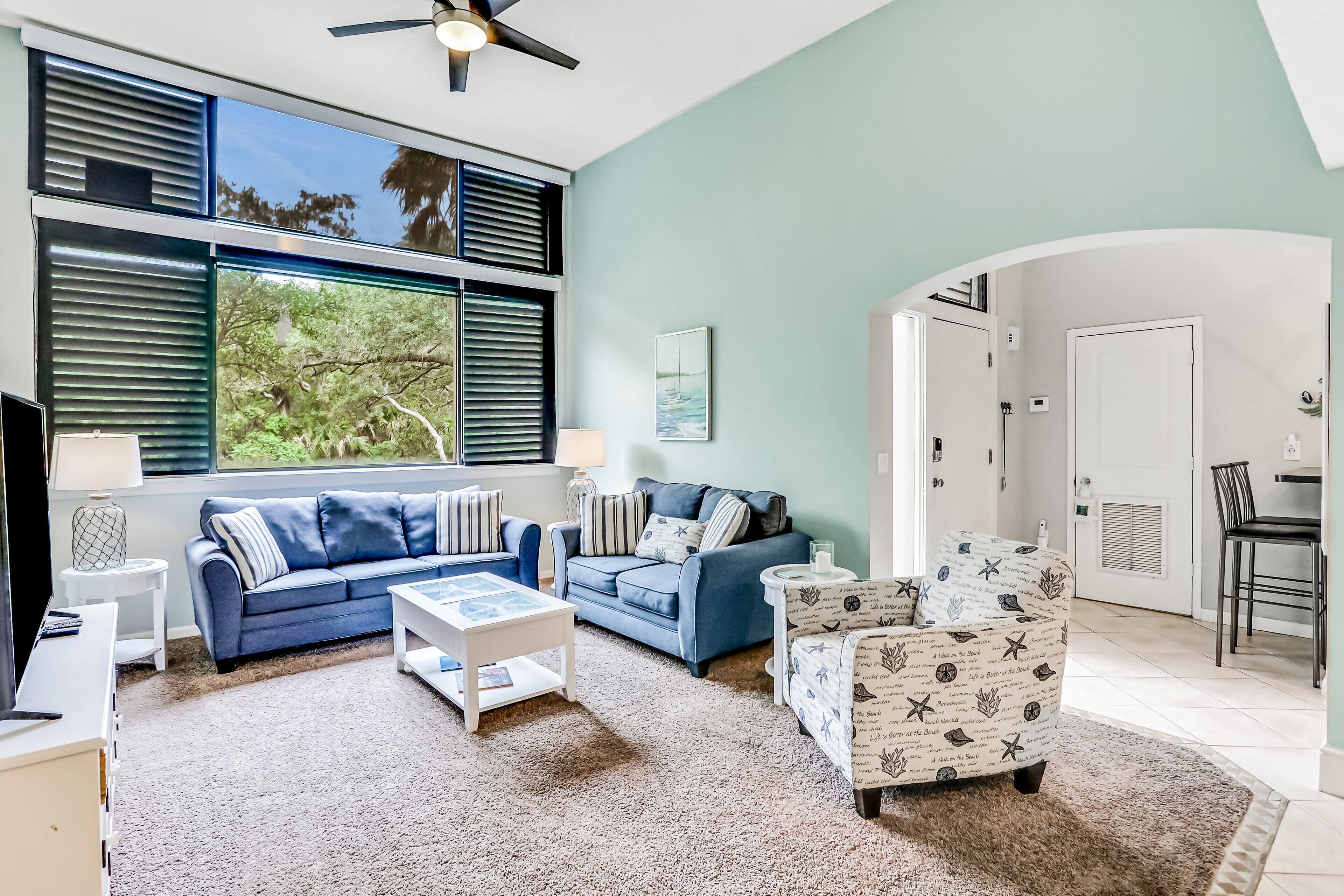 A living room with two sofas, a coffee table, and a patterned armchair.