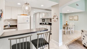 A modern kitchen with white cabinets, a black countertop, and a hanging light fixture. - Charming Amelia Island Plantation Condo With Balcony, AC, Washer/dryer & Pool (Fernandina Beach)