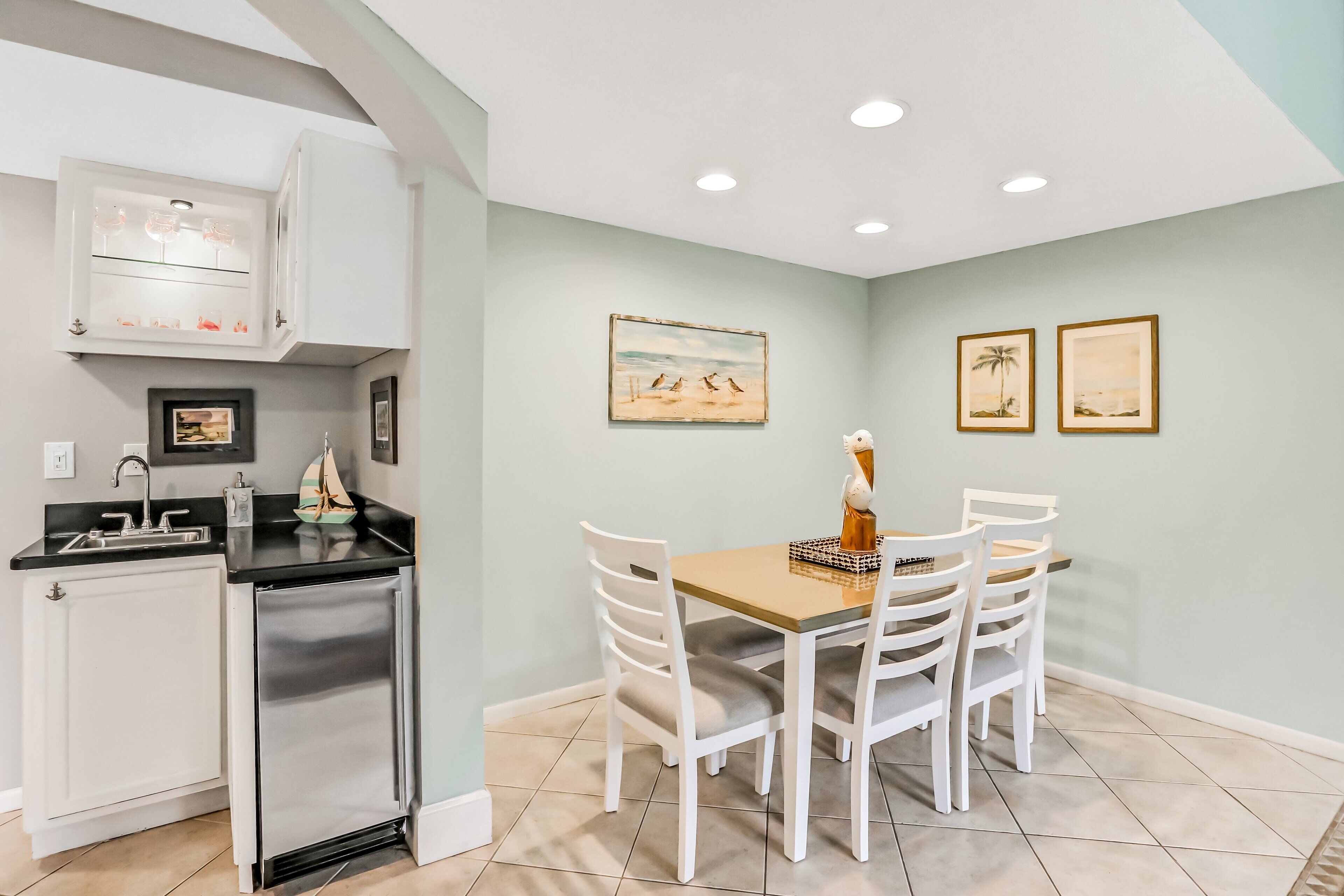 A compact kitchen with white cabinetry, a built-in oven, and a dining area with a wooden table and white chairs.