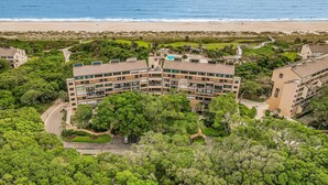 A multi-story hotel with a pool, surrounded by lush greenery and a beach view. - Charming Amelia Island Plantation Condo With Balcony, AC, Washer/dryer & Pool (Fernandina Beach)