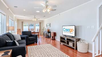 A modern living room with a sofa, TV, and ceiling fans.