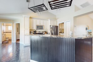 A modern kitchen with white cabinets, a large island, stainless steel appliances, and pendant lighting. - Cheerful Home With Private Pool Close to the Beach & Downtown (St. Augustine)